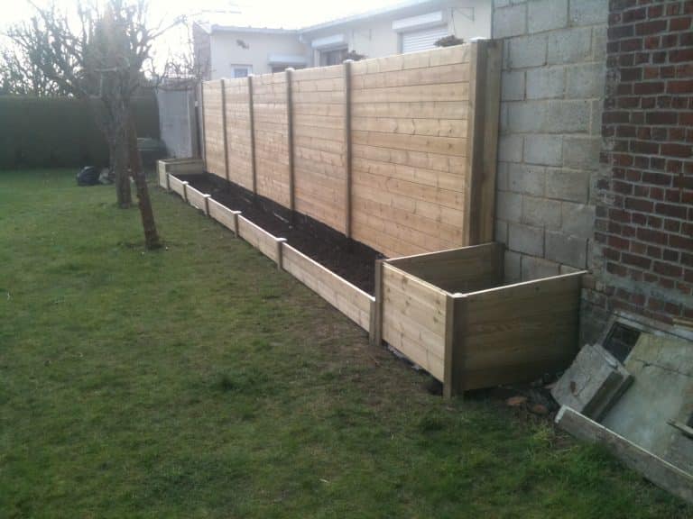 Clôture bois avec des bacs à fleurs à son pied